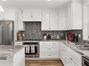 Showing glass tile backsplash & nice stainless appliances