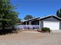 View from driveway of custom hand-painted fence, main house, and attached garage