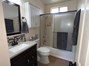 Bathroom featuring vanity, combined bath / shower with glass door, backsplash, and dark tile patterned flooring
