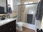 Full bathroom with vanity, shower / bath combination with glass door, dark tile patterned flooring, and tasteful backsplash