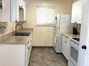 Kitchen featuring white cabinets, white appliances, light countertops, light tile patterned floors, and a textured ceiling